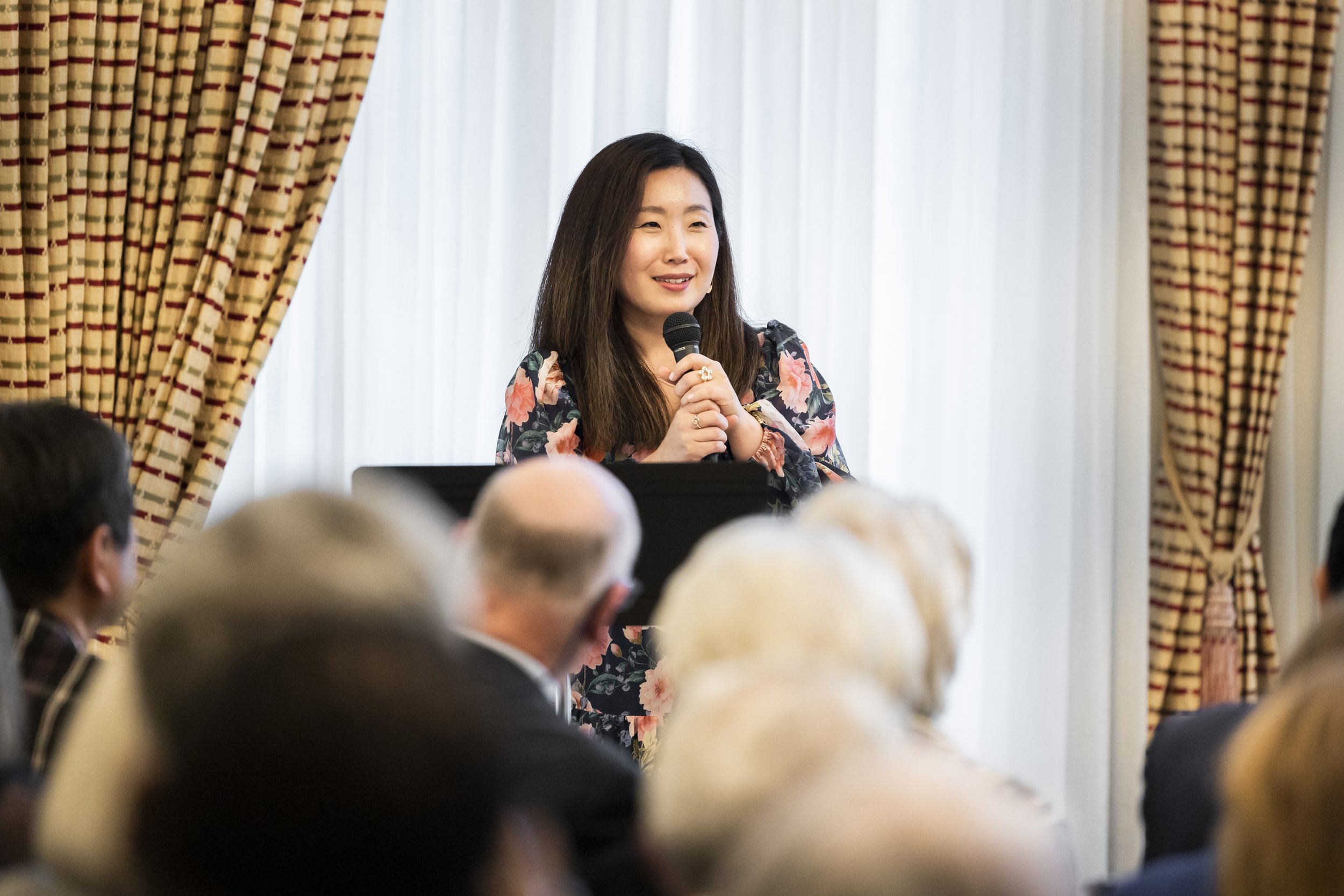 Grace Cho speaking into a microphone at an event.